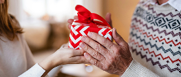 Ein verpacktes Weihnachtsgeschenk wird einem lieben Menschen überreicht